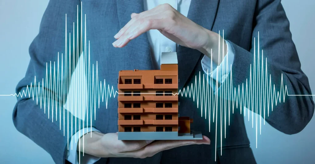 A man in a suit holding a small apartment tower block